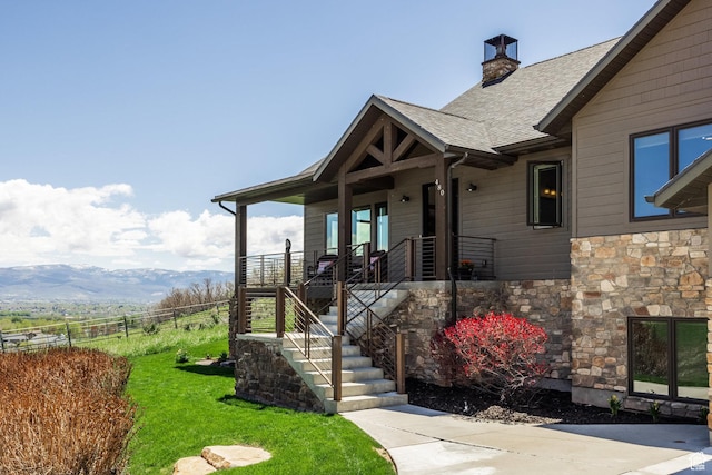 property entrance with stone siding, a chimney, a shingled roof, and a porch