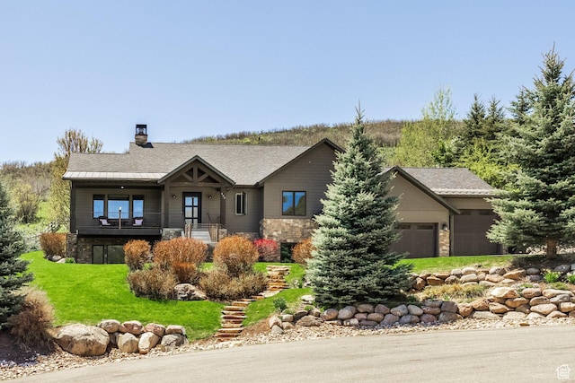 view of front of property with stone siding, an attached garage, a front lawn, and a chimney