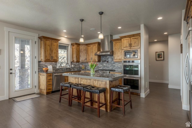 kitchen featuring wall chimney exhaust hood, appliances with stainless steel finishes, tasteful backsplash, baseboards, and recessed lighting