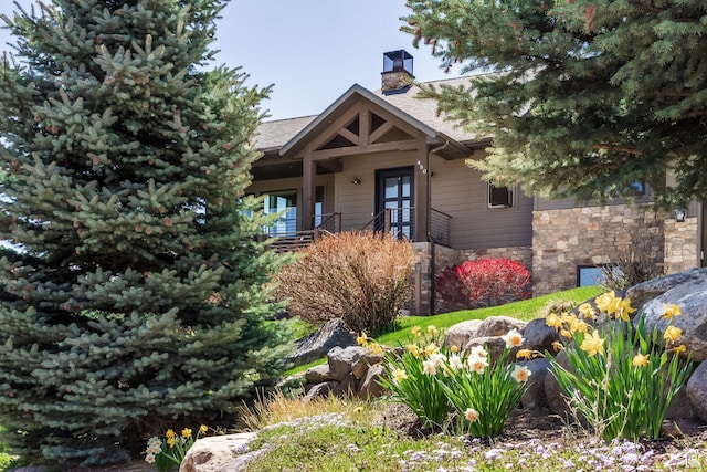 view of front of house featuring stone siding, a chimney, french doors, and a porch