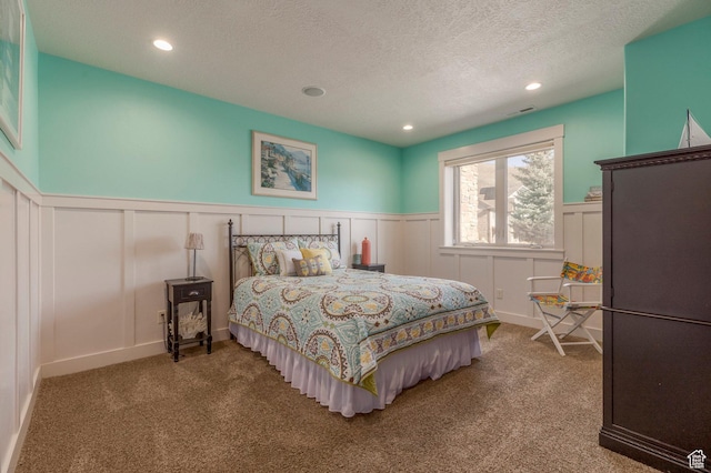 bedroom featuring carpet, a wainscoted wall, a decorative wall, recessed lighting, and a textured ceiling