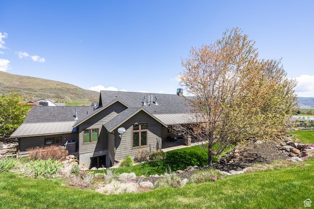 back of house featuring central AC, a mountain view, a shingled roof, and a patio