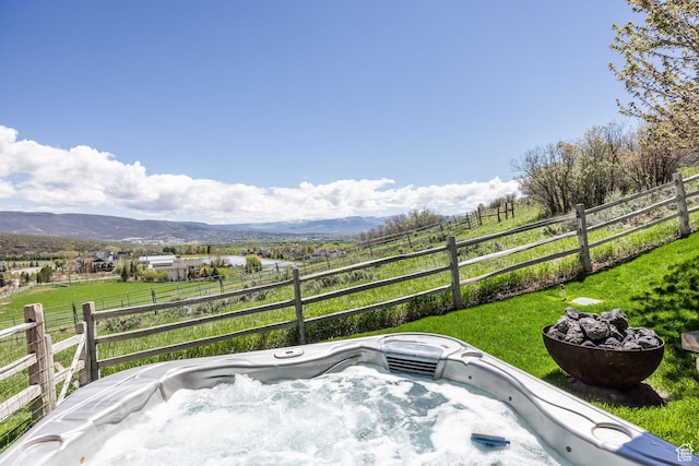 view of patio / terrace featuring a hot tub, a mountain view, and a view of rural / pastoral area