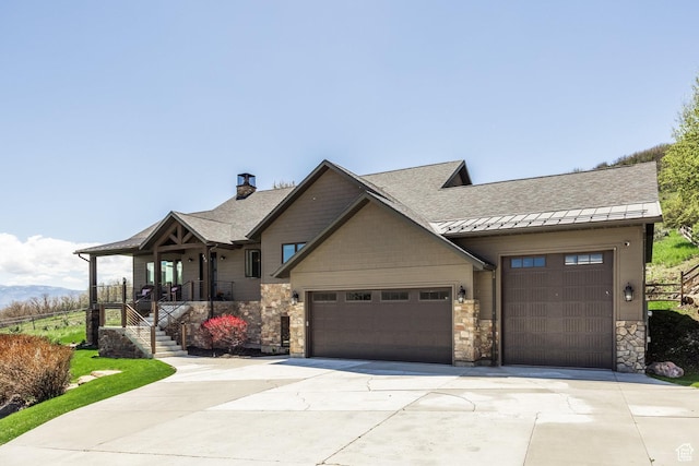 view of front of house featuring driveway, an attached garage, stone siding, a standing seam roof, and a shingled roof