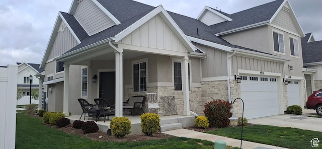 view of front of house with board and batten siding, stone siding, concrete driveway, and a shingled roof