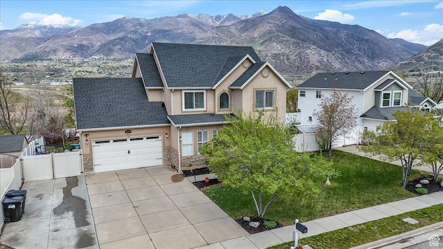 view of front of house with fence, stucco siding, an attached garage, driveway, and a mountain view