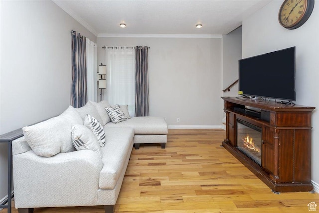 living area with light wood-style flooring, crown molding, and baseboards