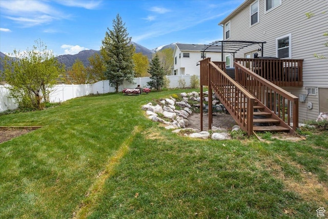 view of yard featuring stairs, a deck with mountain view, a pergola, and a fenced backyard