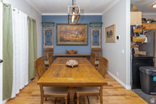 dining area with baseboards, crown molding, and light wood-style flooring