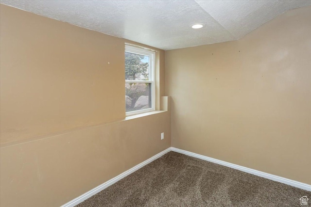 empty room featuring recessed lighting, dark carpet, a textured ceiling, and baseboards