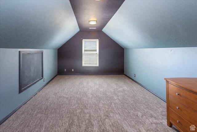 additional living space with lofted ceiling, carpet flooring, a textured ceiling, and baseboards