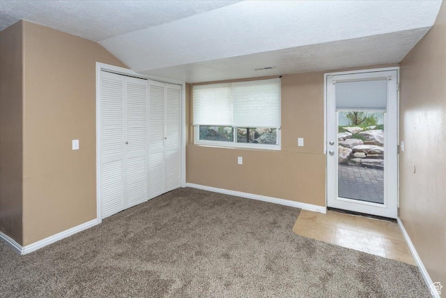entryway featuring lofted ceiling, visible vents, carpet floors, baseboards, and a textured ceiling