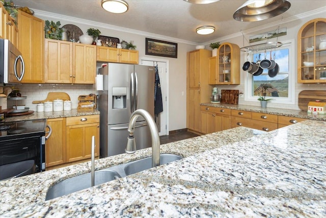 kitchen featuring a sink, tasteful backsplash, light stone counters, crown molding, and appliances with stainless steel finishes