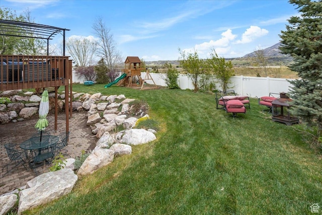 view of yard featuring a fenced backyard, a mountain view, and a playground