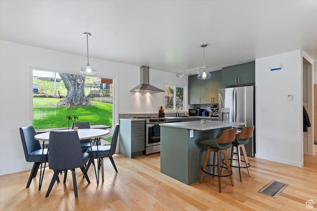 3315 Meadow Dr, Ogden, UT 84403 - kitchen with wall chimney range hood, track lighting, appliances with stainless steel finishes, visible vents, and a kitchen island