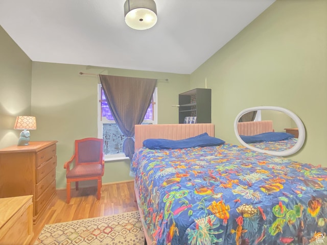 bedroom with vaulted ceiling, wood finished floors, and baseboards