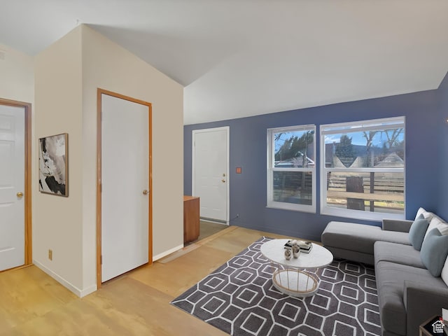 living room with light wood-style floors, lofted ceiling, and baseboards
