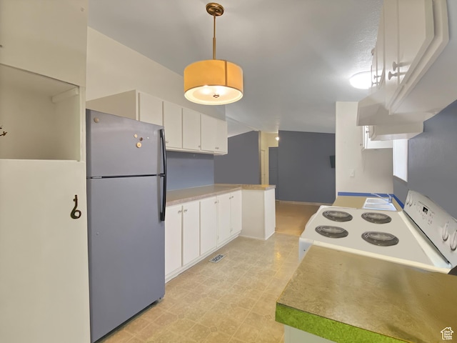 kitchen featuring light countertops, freestanding refrigerator, white range with electric cooktop, pendant lighting, and white cabinetry