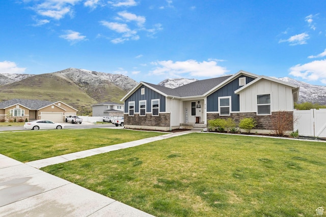 view of front of home featuring board and batten siding, a front lawn, fence, and a mountain view