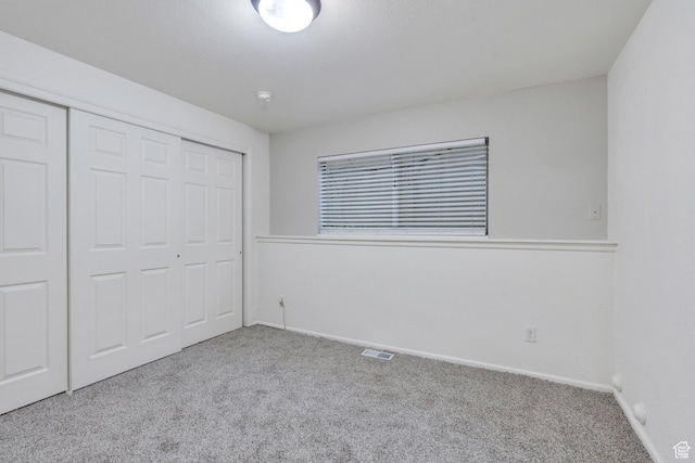 unfurnished bedroom with baseboards, carpet flooring, visible vents, and a closet