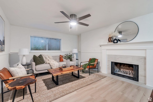 living area featuring a premium fireplace, wood finished floors, and ceiling fan