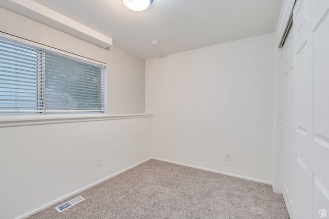 unfurnished bedroom with baseboards, visible vents, carpet, and a closet