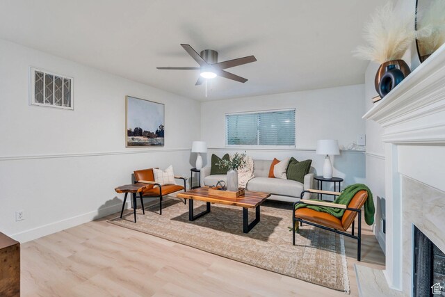living room featuring baseboards, a ceiling fan, wood finished floors, and a fireplace