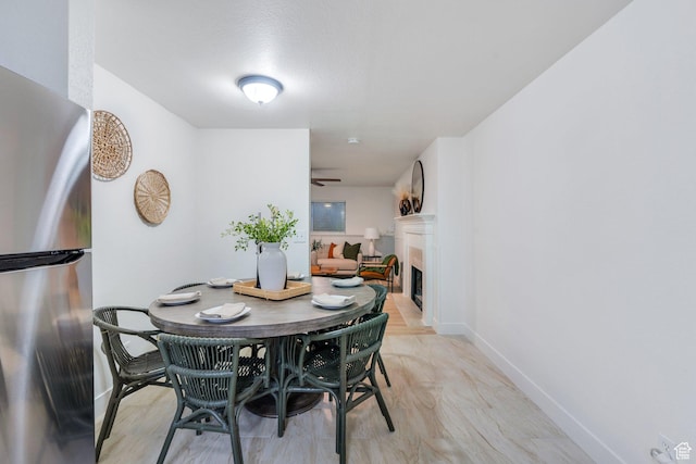 dining room with ceiling fan, baseboards, and a fireplace