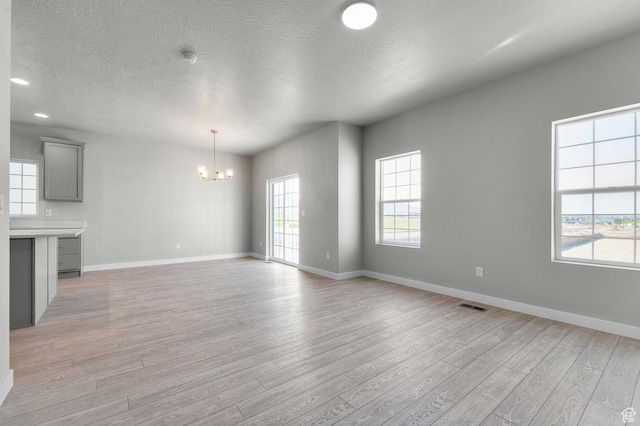 6622 W Spring Snow Ln, Herriman, UT 84096 - unfurnished living room featuring a chandelier, light wood-type flooring, baseboards, a textured ceiling, and recessed lighting