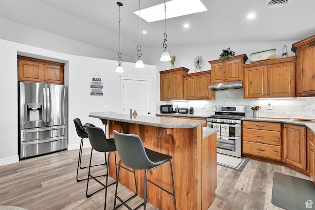 4990 W 12000 N, Tremonton, UT 84337 - kitchen with backsplash, under cabinet range hood, lofted ceiling with skylight, and stainless steel appliances