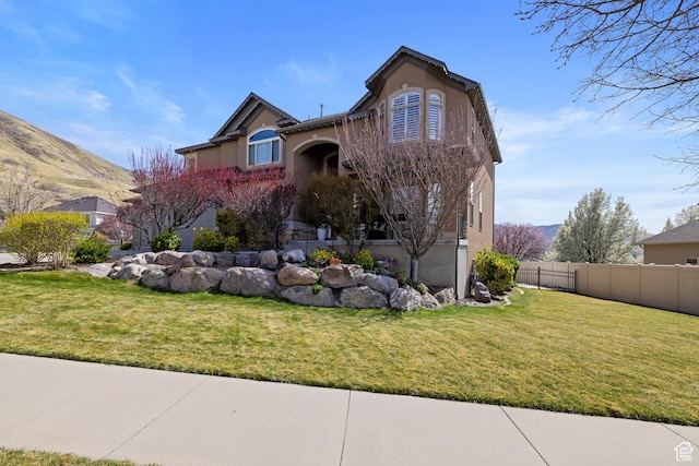 traditional home featuring stucco siding, a front lawn, and fence
