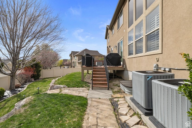 view of yard with fence, a wooden deck, stairs, and central AC unit