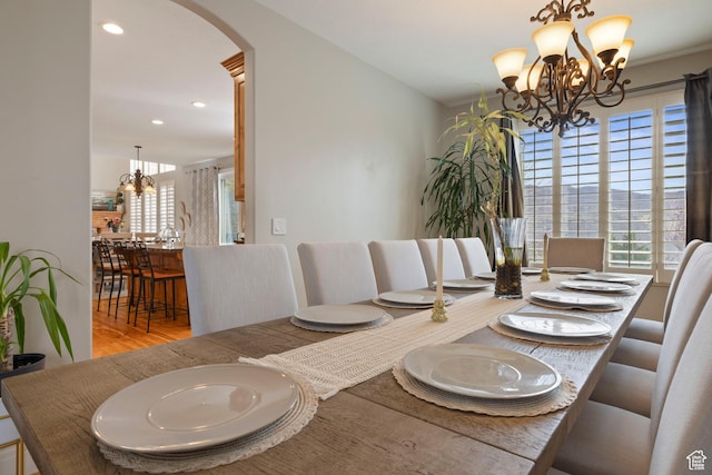 dining room featuring arched walkways, wood finished floors, recessed lighting, and an inviting chandelier