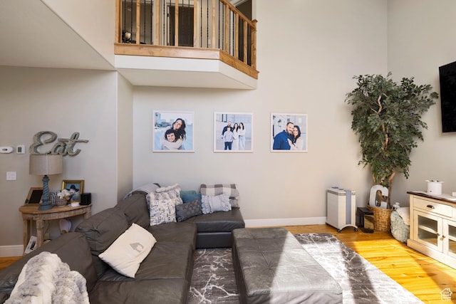 living room with wood finished floors, a towering ceiling, and baseboards