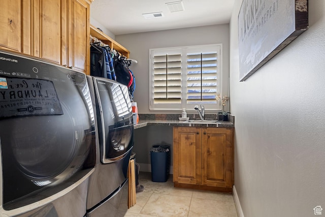 clothes washing area featuring cabinet space, visible vents, washing machine and clothes dryer, and a sink
