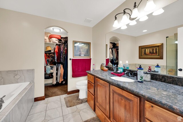 full bathroom with a spacious closet, baseboards, a garden tub, vanity, and tile patterned flooring