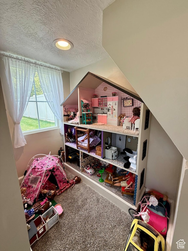 recreation room featuring a textured ceiling, lofted ceiling, and carpet floors