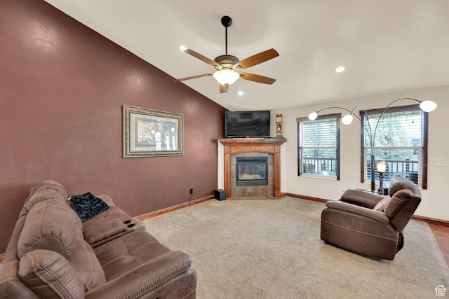 carpeted living area featuring ceiling fan, a tiled fireplace, vaulted ceiling, and baseboards