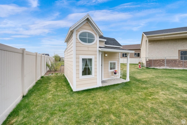 back of property with roof with shingles, a yard, and a fenced backyard