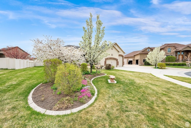 view of front facade with stucco siding, fence, a front yard, concrete driveway, and an attached garage