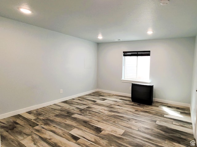 unfurnished room featuring recessed lighting, wood finished floors, and baseboards