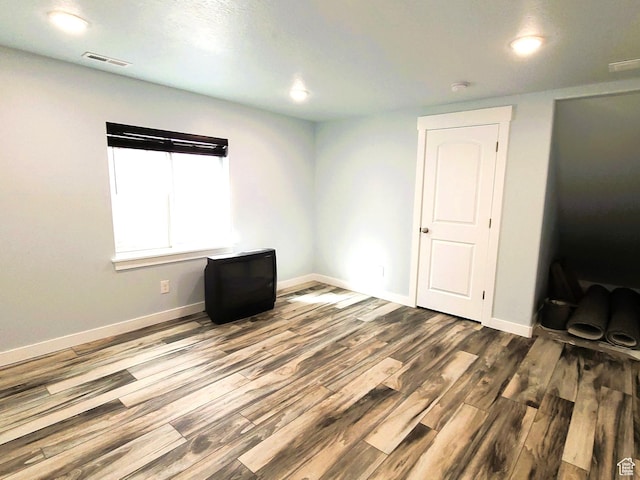 spare room with baseboards, wood finished floors, visible vents, and recessed lighting
