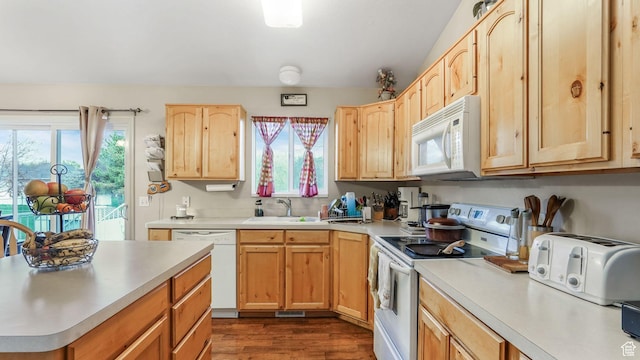 kitchen with light countertops, light brown cabinetry, a sink, and white appliances