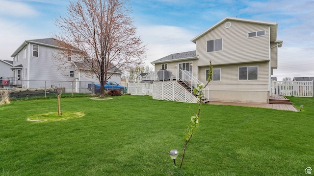 rear view of property featuring a fenced backyard, stairs, and a lawn
