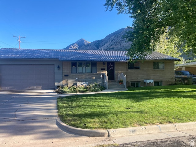 715 Oak Dr, Brigham City, UT 84302 - raised ranch featuring an attached garage, driveway, a front yard, a mountain view, and metal roof
