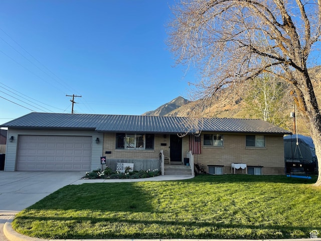 715 Oak Dr, Brigham City, UT 84302 - view of front of property featuring a front lawn, a mountain view, driveway, metal roof, and a garage