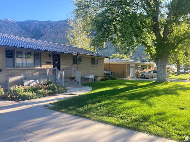 715 Oak Dr, Brigham City, UT 84302 - view of front of house featuring a front lawn, brick siding, metal roof, and a mountain view