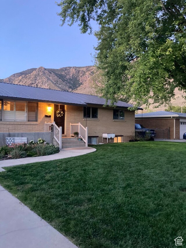 715 Oak Dr, Brigham City, UT 84302 - view of front facade with brick siding, a front yard, metal roof, and a mountain view