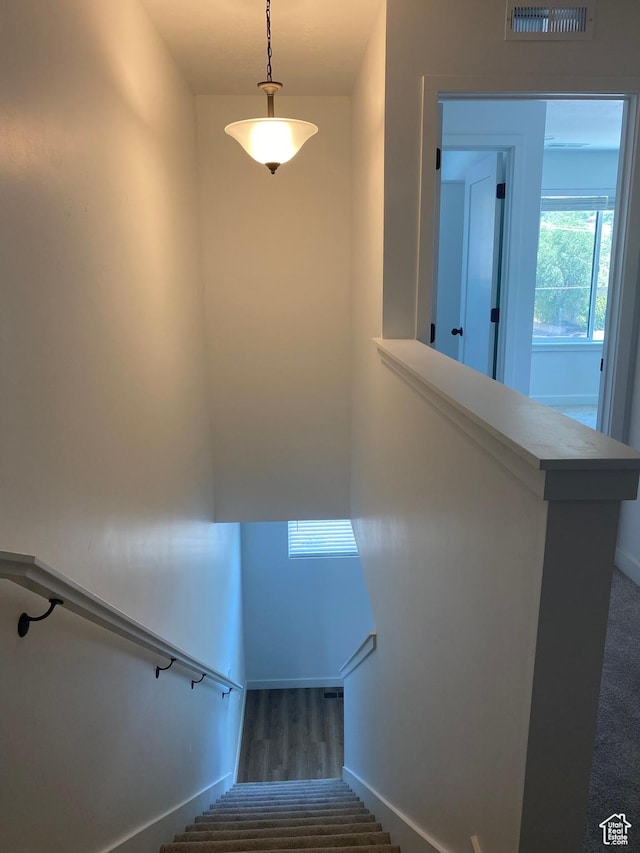 stairway featuring baseboards, wood finished floors, and visible vents