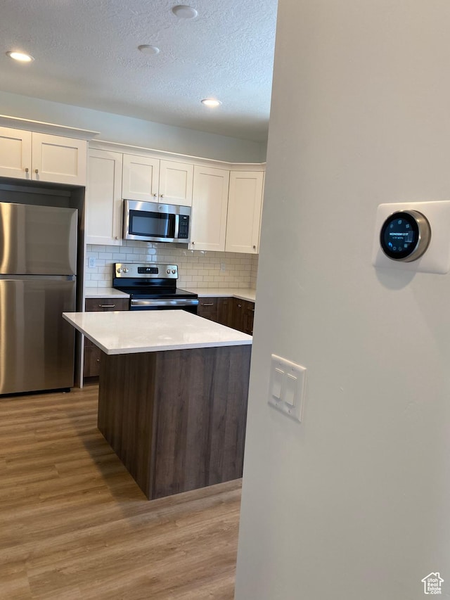 kitchen featuring light countertops, light wood-type flooring, white cabinets, and stainless steel appliances